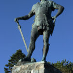 Statue av mann i enkel rustning og sverd.